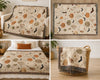 A four-panel collage showing a woven throw blanket with a Halloween print in multiple home settings. The blanket has a cream background with orange pumpkins, black bats, brown leaves, and beige moon and sun motifs, finished with dark fringe.