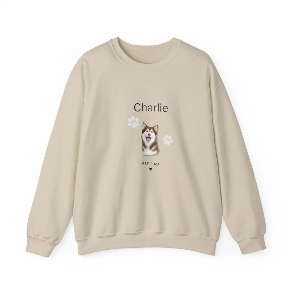 A beige crewneck sweatshirt featuring a custom graphic of a Husky dog with the name 'Charlie' and paw prints on the front, displayed against a solid white background.