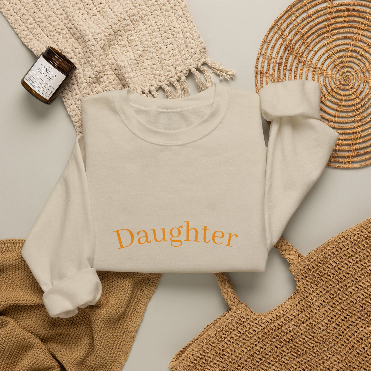 Beige sweatshirt on a light gray surface with a woven mat and bottle of shampoo.